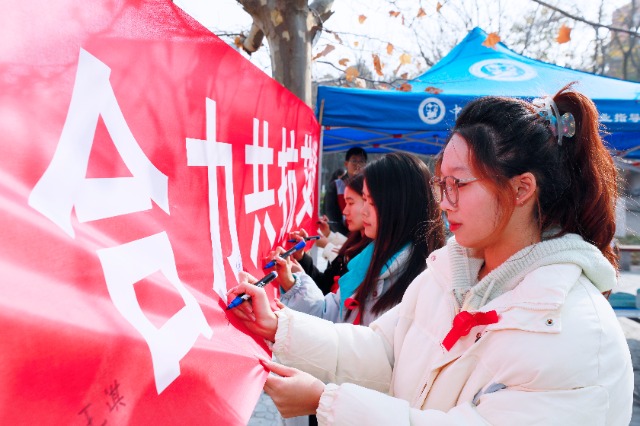 20231127中國石油大學(xué)（華東）青年學(xué)子在合力共抗艾滋的條幅上簽字，表達(dá)抗擊艾滋病的決心和信心  .jpg