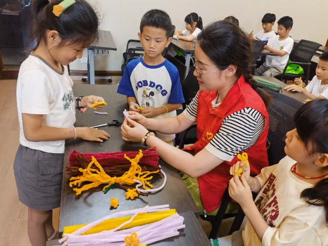 7月12日，在泰州市海陵區(qū)城東街道林湖社區(qū)，泰州市大浦小學(xué)“綠葉”暑期公益班的老師正在教孩子們一起做手工2（拍攝者：泰州市大浦中心小學(xué)  陳惠婷）.jpg